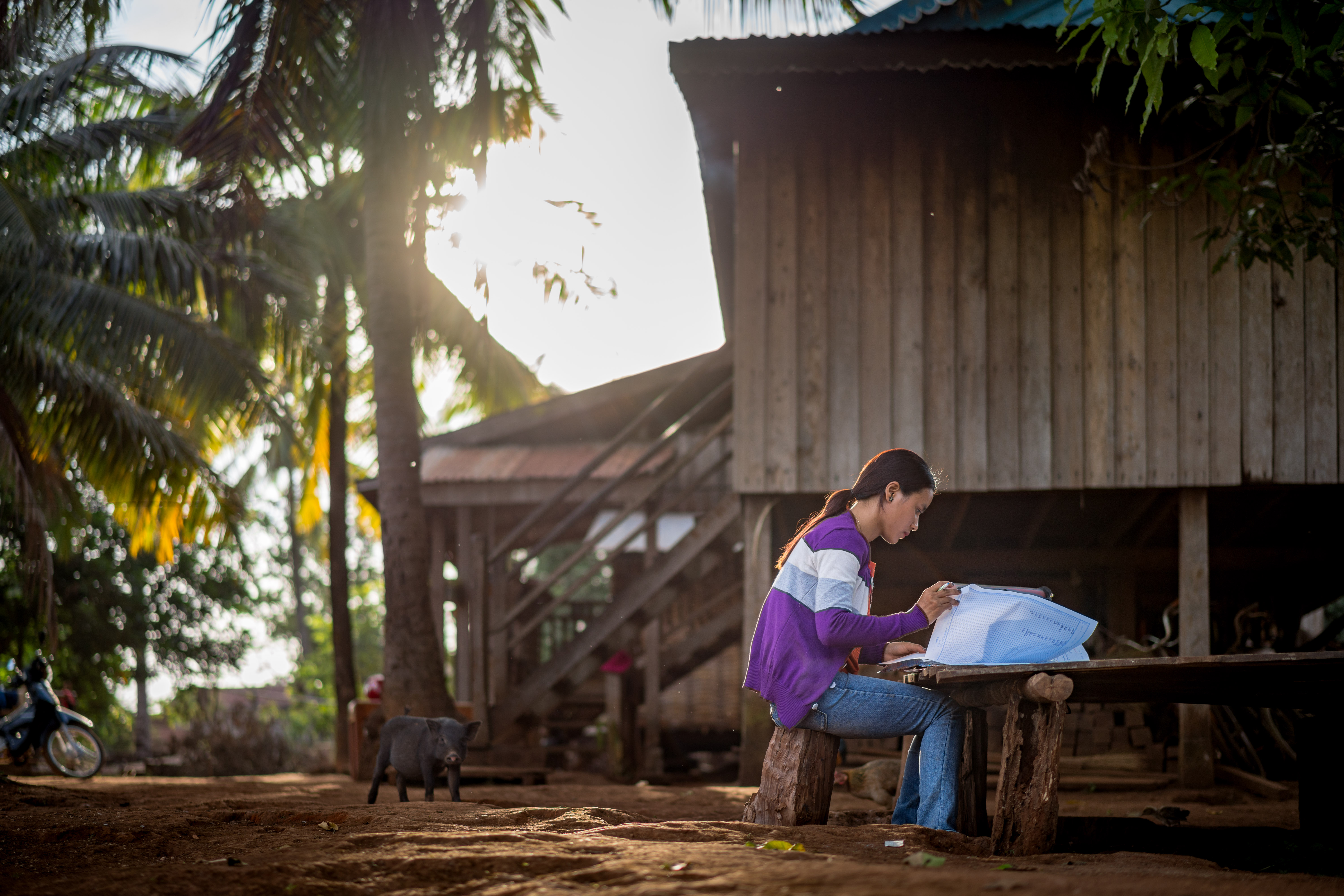 15 November 2018, Poy commune, Ochum district, Ratanakiri province, Cambodia. After working on the farm with her family, Chea Lach heads home and does her marking for the day before it gets too dark.