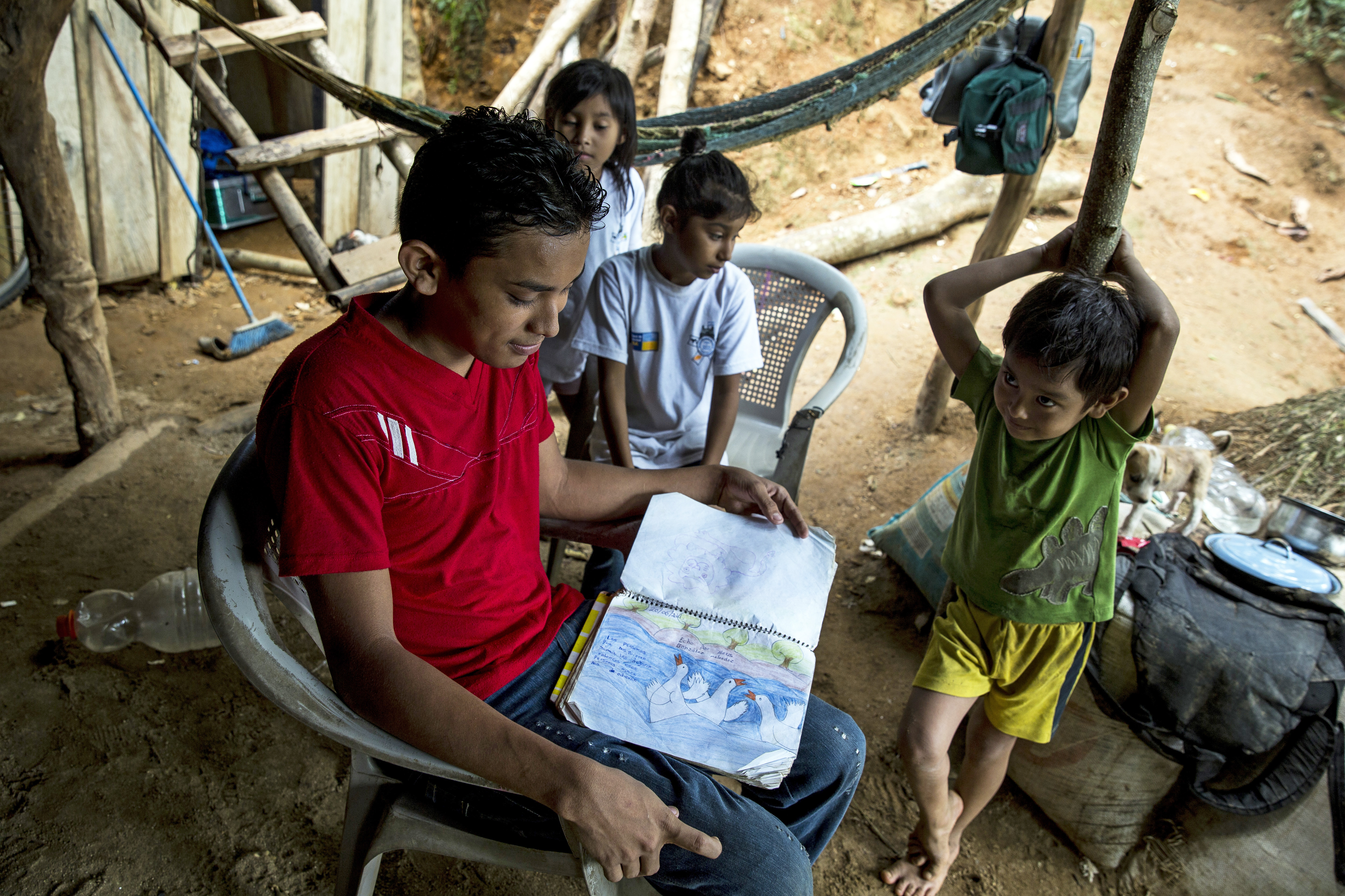 (Centre, wearing read) Alexis, 18, looks at his scrapbooks with his siblings at home in Omoa, Honduras on June 27th, 2016. 