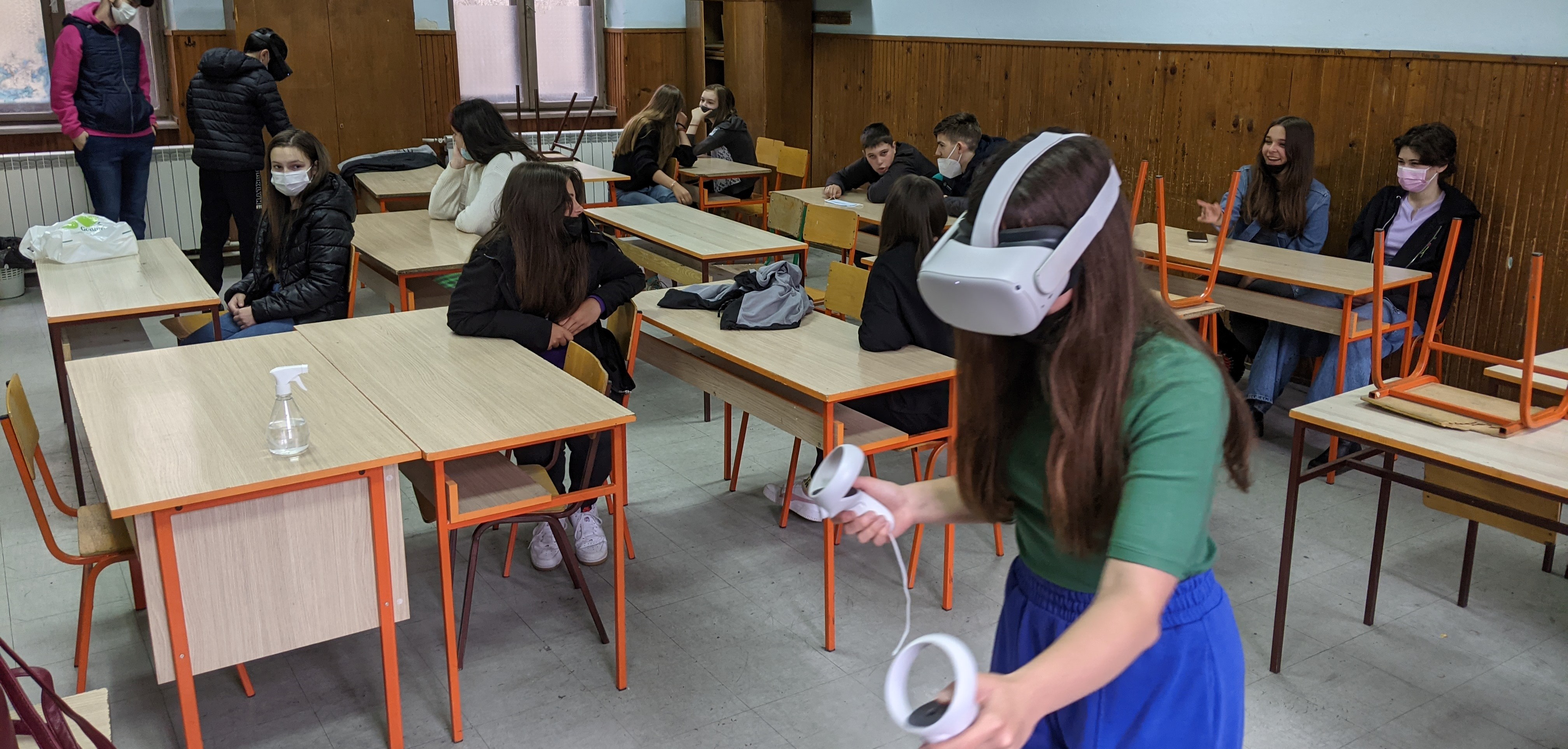 A child using a VR headset in a classroom with fellow students watching her 