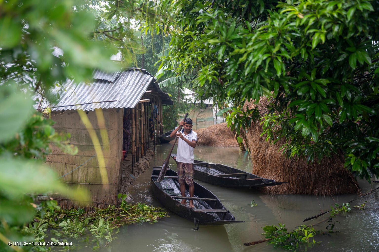 A man is taking a boat to travel through the flood waters, in Sylhet, in June 2024