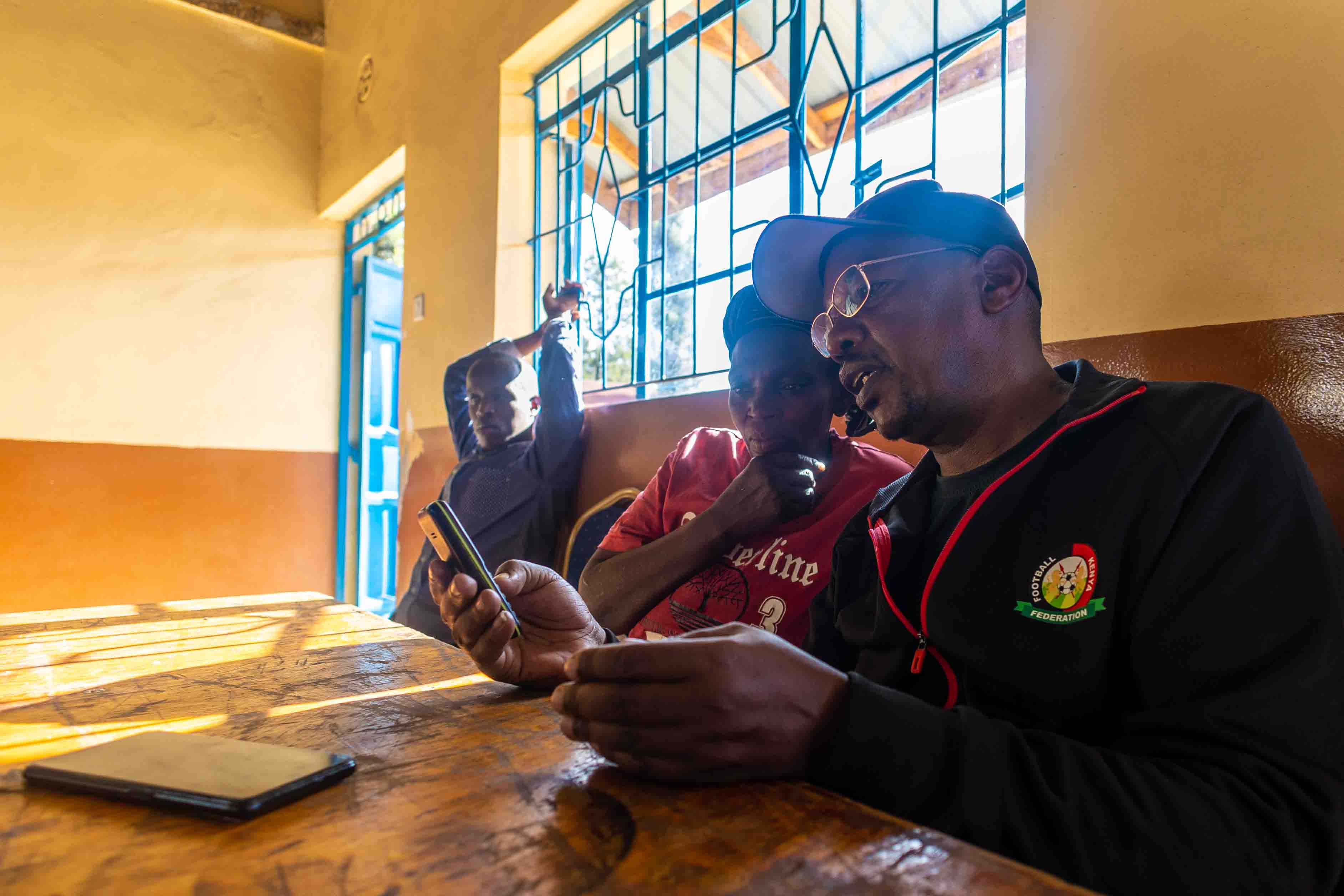 Two beneficiaries checking the conversion of received funds during test session. December 2025, Nairobi,Kenya.