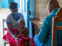 A mother holds her child during a medical check up