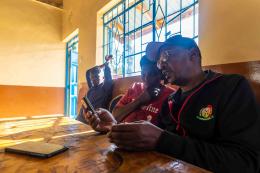 Two beneficiaries checking the conversion of received funds during test session. December 2025, Nairobi,Kenya.